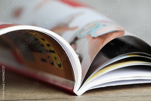 One open magazine on wooden table, closeup
