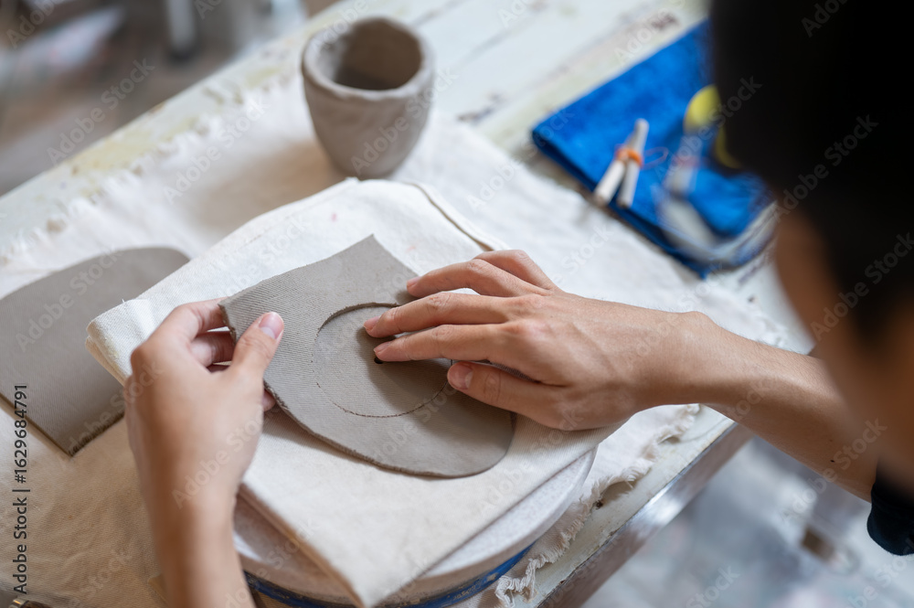 Obraz premium Pottery artist taking out circle clay from slab on throwing wheel at work table in a class or studio