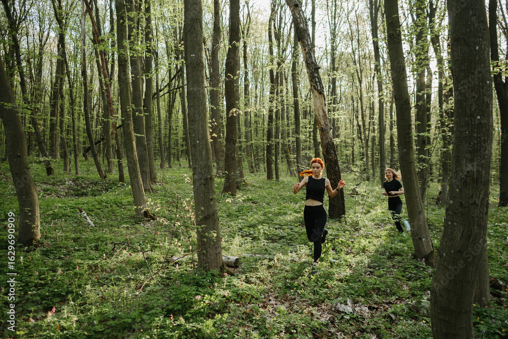 Fototapeta premium Women jogging through a sunlit forest trail