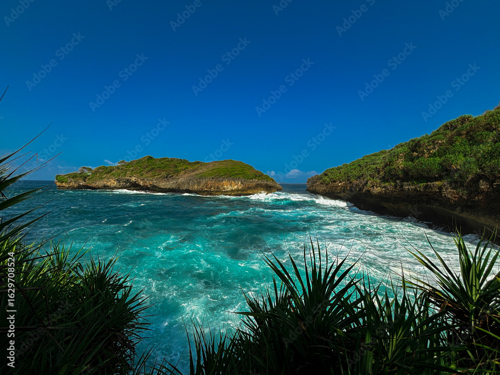 Fototapeta premium Seaside Serenity: A breathtaking coastal vista unfolds, where turquoise waters meet rugged land, under a vibrant blue sky, inviting the viewer to immerse themselves in nature's spectacle.