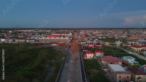 Aerial perspective of a new highway being constructed next to a high end neighborhood in Guyana- 4K 