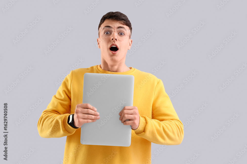 Shocked young man with laptop on light background Shocked young man with laptop on light background