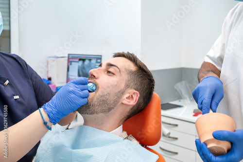 Fotografie Man receiving oral dental impression from two dentists in modern clinical settin