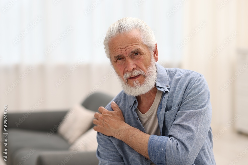 Fototapeta premium Senior man suffering from shoulder pain at home