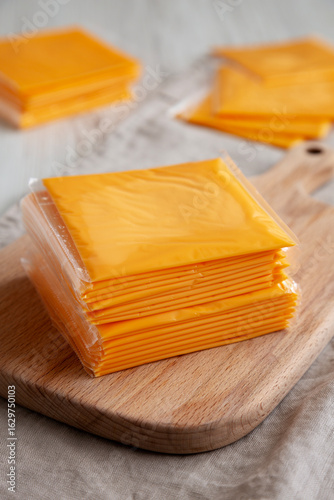 Stack of American Cheese Slices in Wrappers, side view.