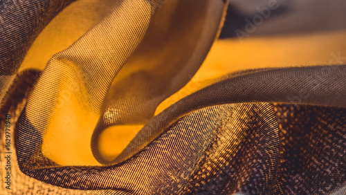 Abstract close-up of layered fabric with yellow and brown tones, creating a textured and flowing composition.
