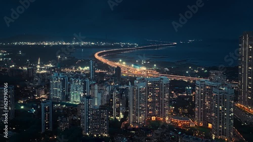 Drone hyperlapse aerial shot of Atal Setu in Mumbai at night, showcasing the dynamic cityscape illuminated with vibrant lights. The footage captures the fast-paced movement of traffic and clouds.