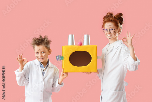 Fotografie Funny inventors with burnt faces and device showing OK on pink background