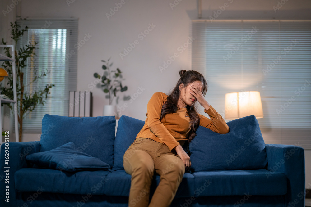 Obraz premium Young woman feeling sad and depressed on sofa at home