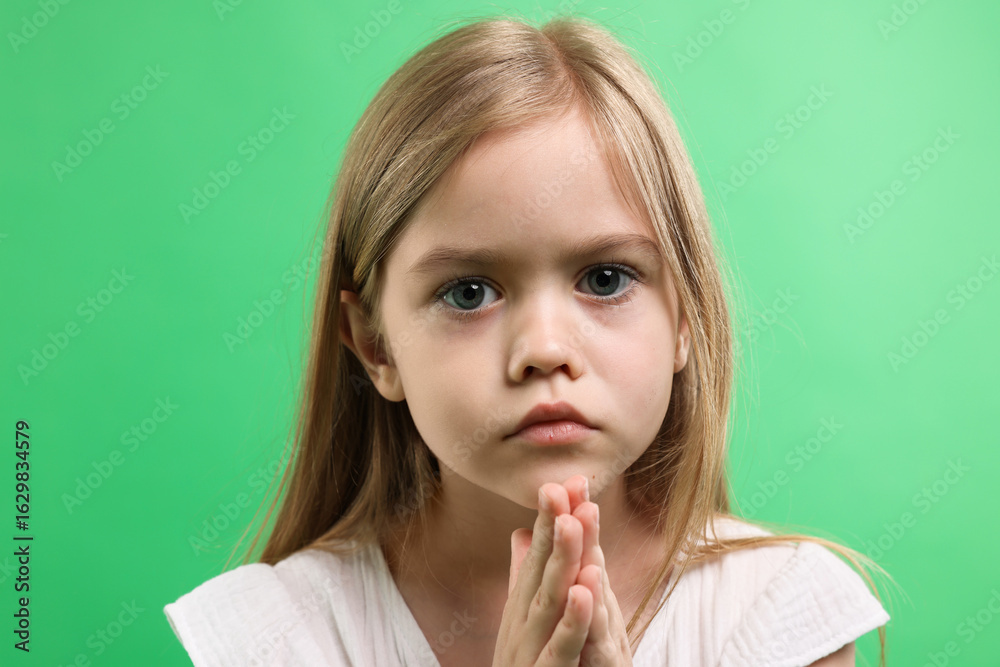 Little girl with clasped hands apologizing on green background, closeup Little girl with clasped hands apologizing on green background, closeup