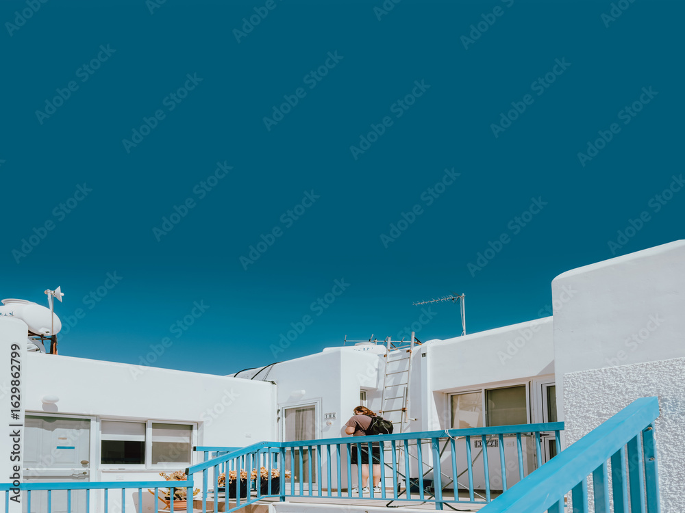 Obraz premium Modern white Mediterranean architecture with bright blue railings and deep sky