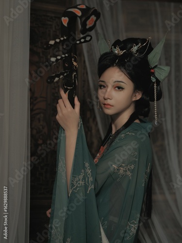 Obraz na płótnie Young Asian woman in elegant traditional attire, holding a prop Chinese word means flower