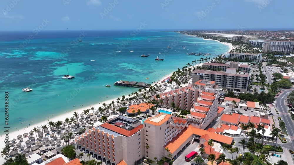 Naklejka premium Palm Beach In Oranjestad Caribbean Netherlands Aruba. Modern Glass Skyscraper Soars Above A Bustling City. Paradise Landscape Idyllic Amazing. Paradise Coast. Oranjestad Caribbean Netherlands.