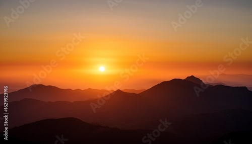 a sunrise over a mountain range the sun is half visible casting a bright orange glow across the sky and silhouetting the mountains