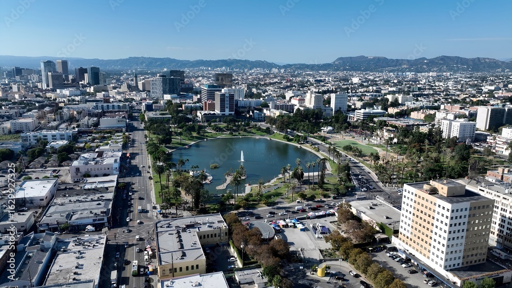 Naklejka premium Macarthur Park Lake In Los Angeles California United States. Aerial View Of A City Park Surrounded By Busy Streets And Buildings. Business Sky Clouds Downtown Cityscape. Outdoor Downtown Panning Wide.