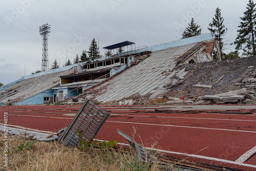 Old broken abandoned sports football stadium with stands and seats. War in Europe between Russia and Ukraine. Military conflict. Destroyed building after missile attack and air strike.
