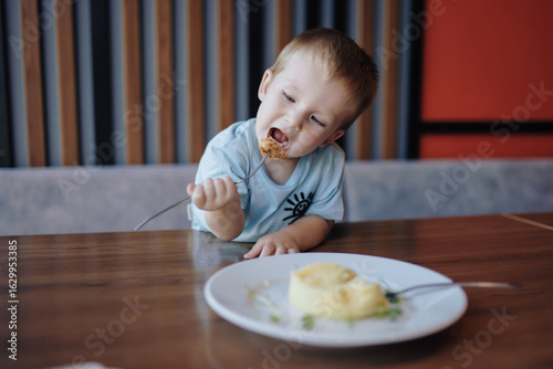 A little boy eating food in cafe