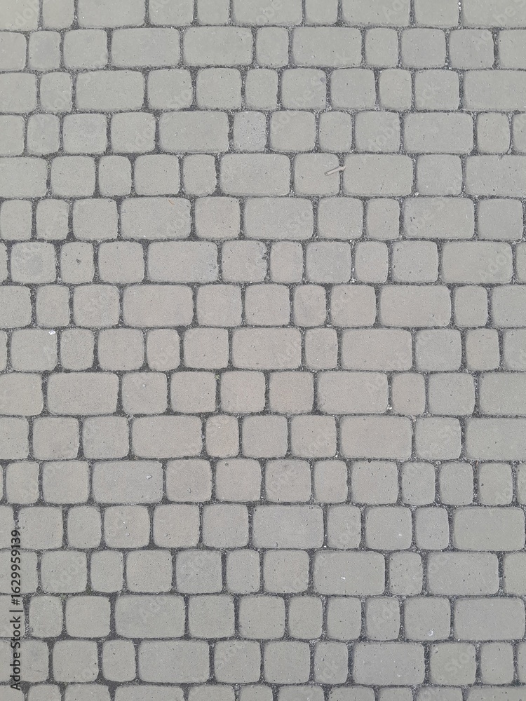 Fototapeta premium Texture of street tiles. Pattern of gray sidewalk tiles close up