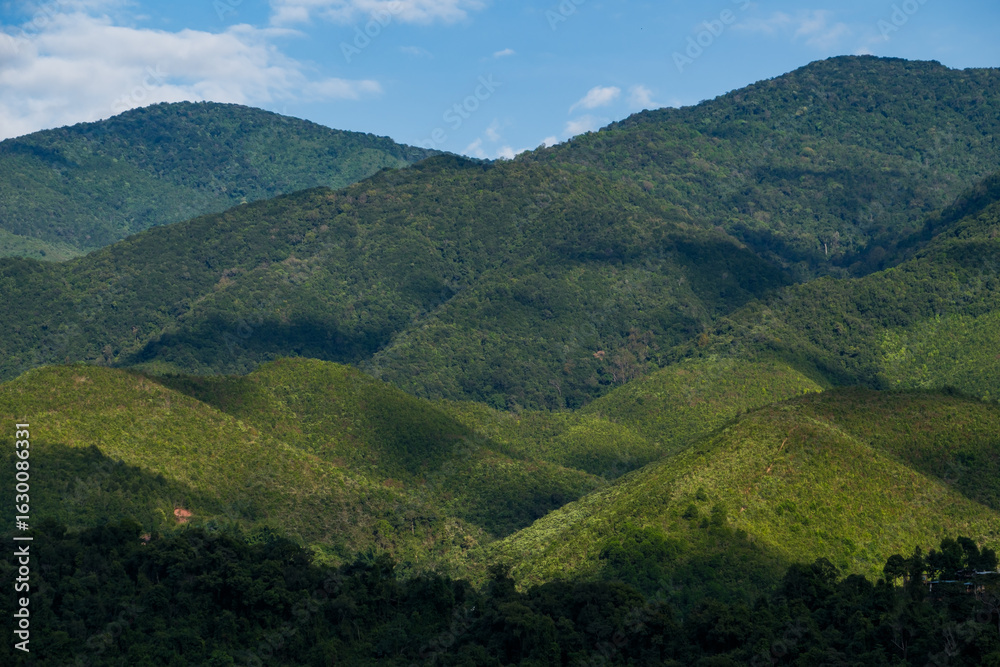 Fototapeta premium many cabin huts of a small village on the one of slope of complex mountain in sun shine and shade of clouds