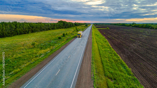 Foto trucks drive along the road in the summer, surrounded by green fields