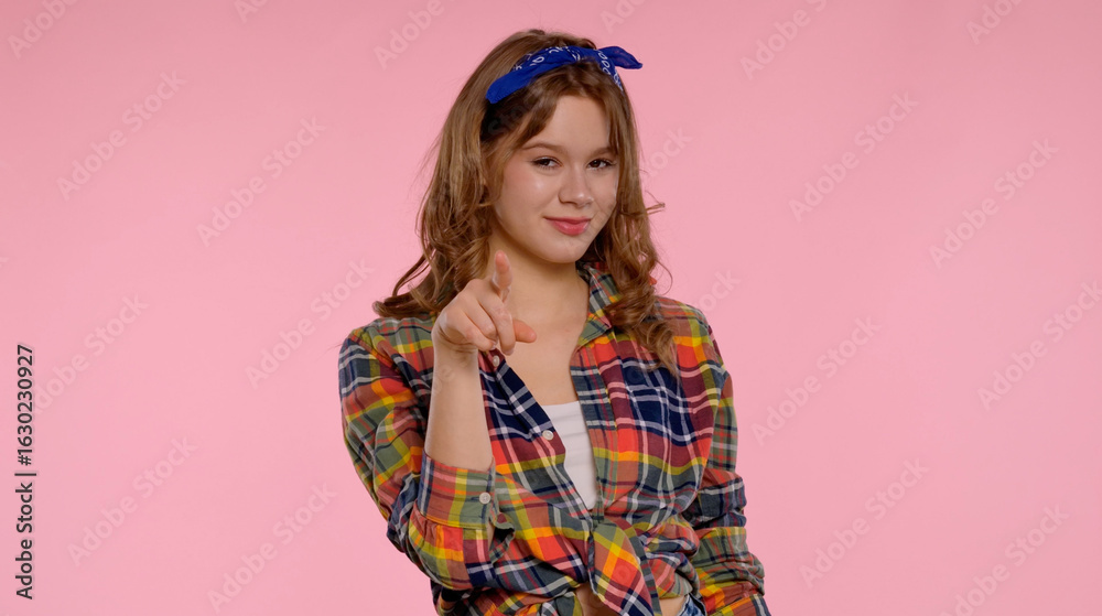 Cheerful Young Woman Pointing and Smiling in Plaid Shirt Cheerful Young Woman Pointing and Smiling in Plaid Shirt