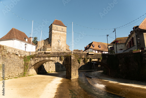 Obraz na plátně View of the impressive medieval architecture of the small stone houses with a beautiful riverside bridge in the touristy southern French village of Sales de Bearn at sunset