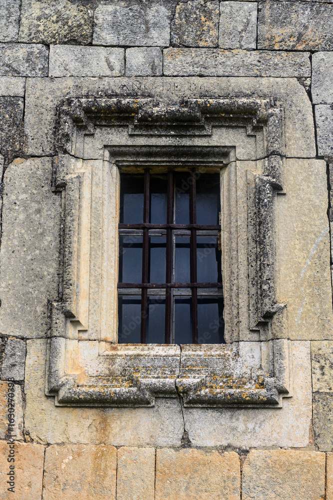 Naklejka premium Stone-framed window with iron bars on San Miguel Church in Villavega de Ojeda
