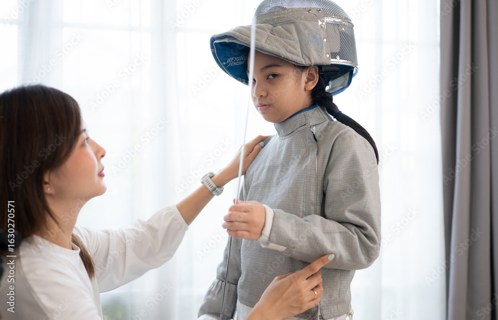 Obraz premium A girl in fencing gear with their mother preparing sports equipment