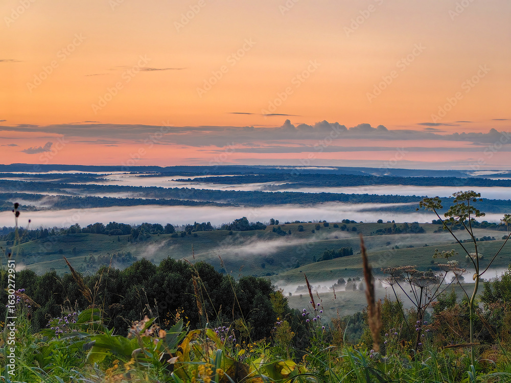 Obraz premium The sun rises over a dreamy, misty landscape filled with rolling hills and trees.