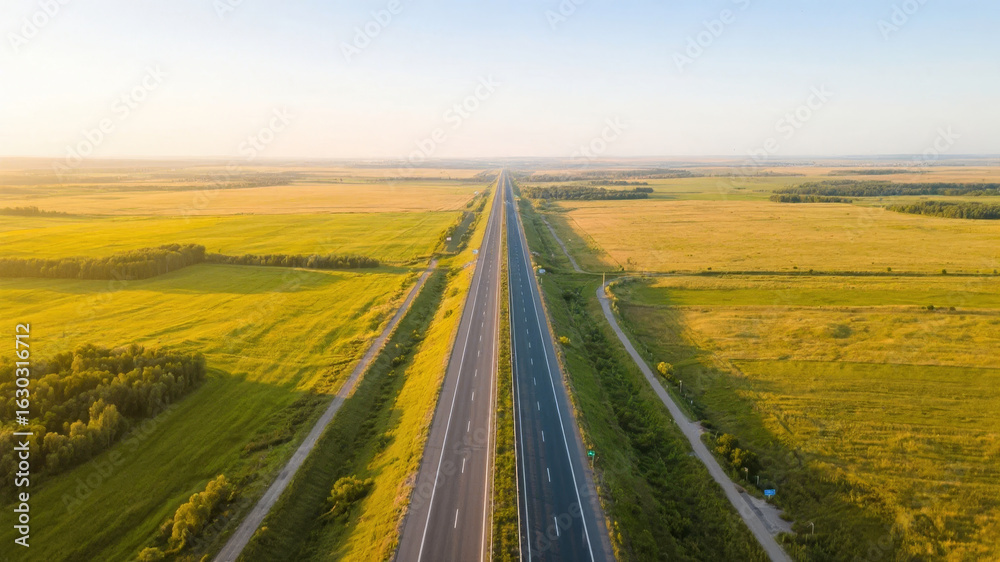 Naklejka premium Aerial View of a Straight Highway Cutting Through Golden Fields
