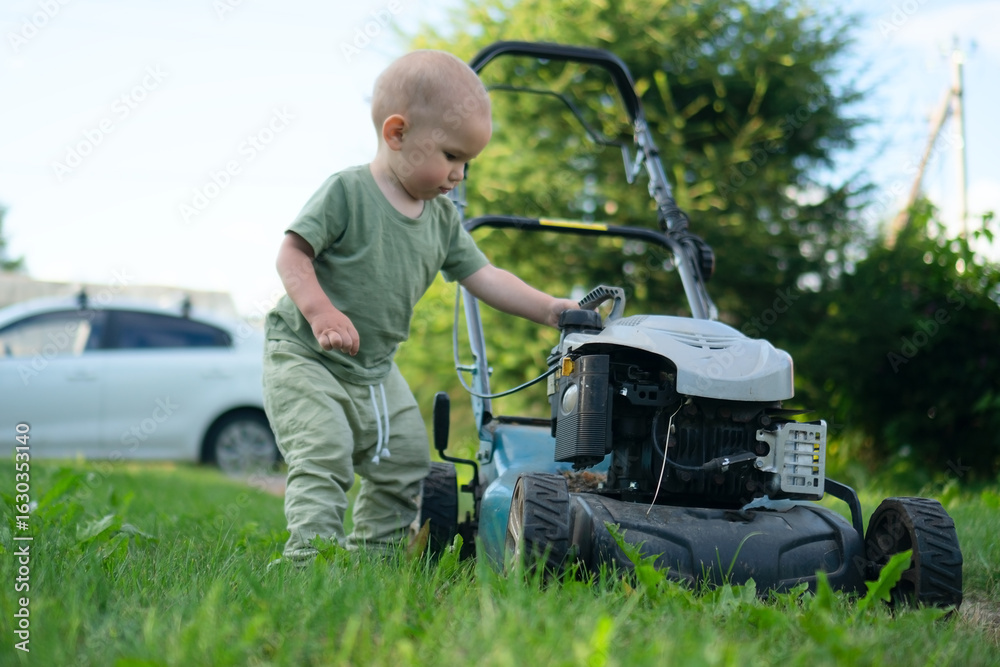 Fototapeta premium Little child in nature exploring garden lawnmower with innocent curiosity. Safe outdoor environment concept for kids and proper lawn maintenance.