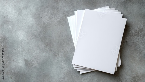Stack of blank white brochures on a gray textured surface