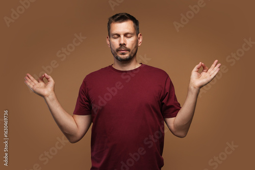 Panic attack. Man meditating to calm down on brown background