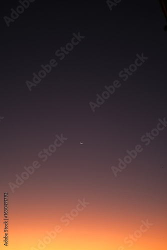 Minimalist crescent moon centered in a colorful gradient twilight sky from purple to orange.