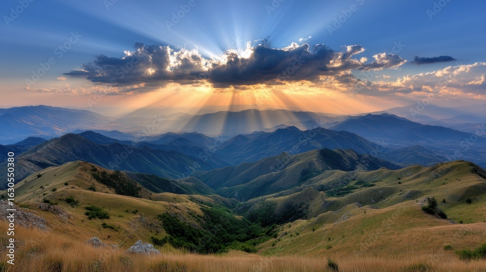Obraz premium Sun rays break through clouds over rolling green mountains at sunrise or sunset