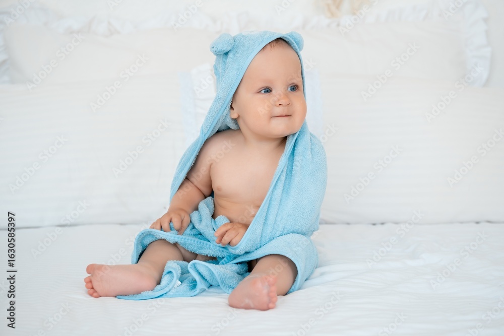 baby boy in a blue bath towel after washing on a white bed, baby hygiene, baby bathing baby boy in a blue bath towel after washing on a white bed, baby hygiene, baby bathing