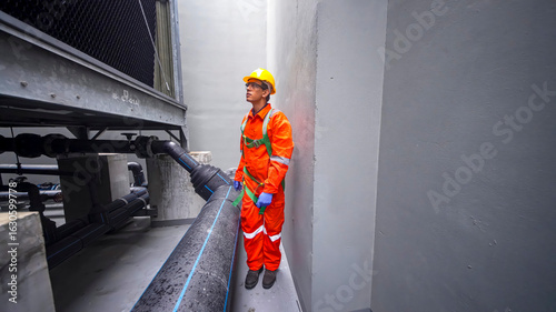 Worker in safety gear inspects industrial pipes in a confined space at a facility