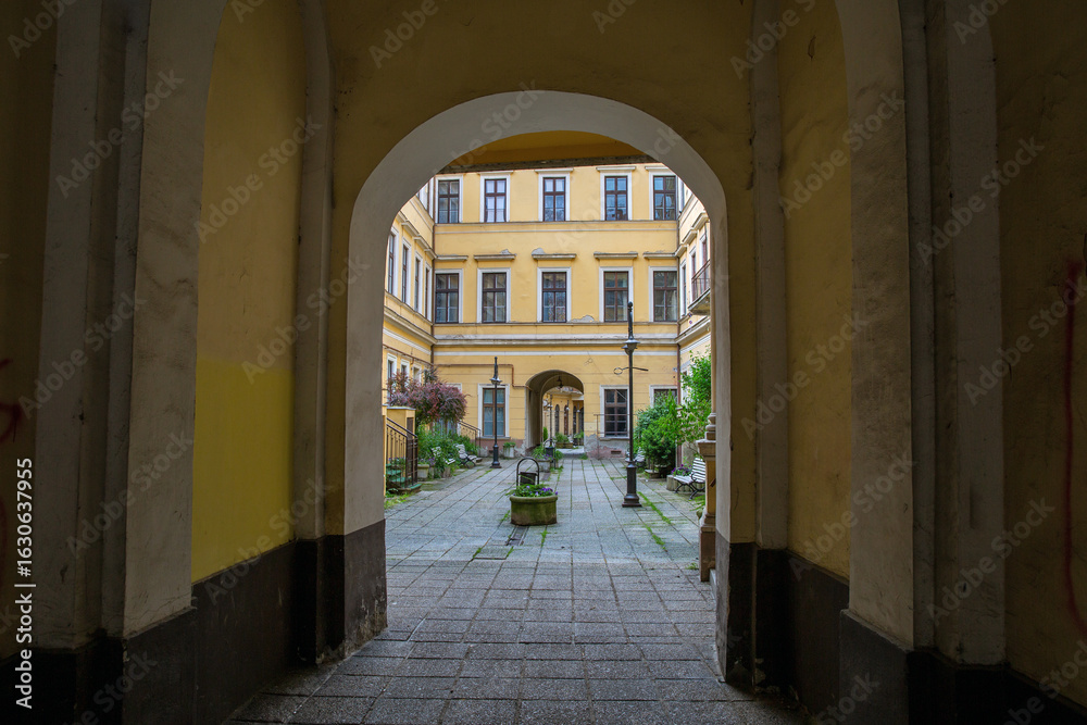 Fototapeta premium Historic courtyard viewed through arched entrance passageway. Nagykanizsa, Hungary.