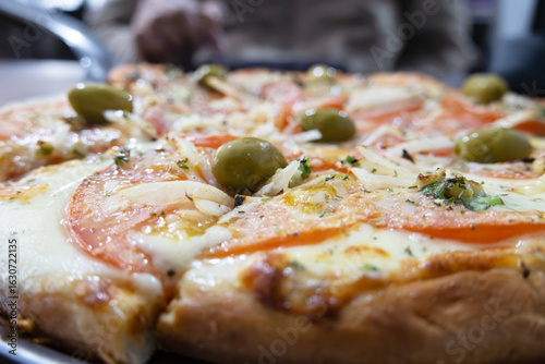 A sliced Argentinian Neapolitan pizza photographed close up with various parts blurred out
