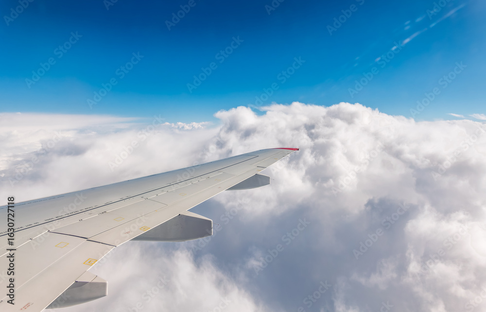 Fototapeta premium View from the airplane window at a beautiful cloudy sky and the airplane wing