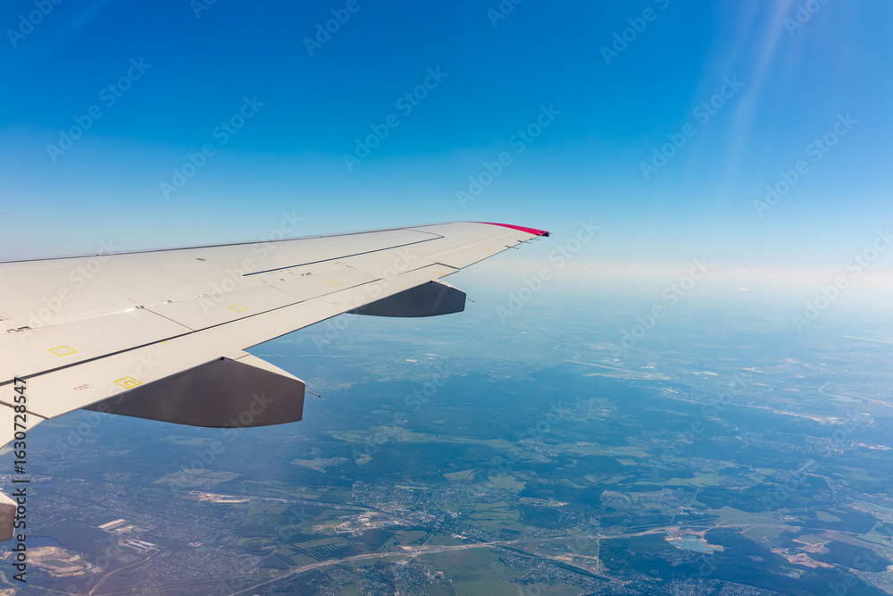 Obraz premium View from the airplane window at a beautiful blue clear sky and the airplane wing