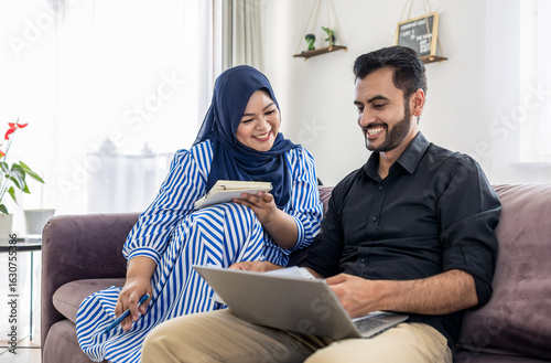 Tableau sur toile Muslim Couple using laptop Together on Sofa at Home