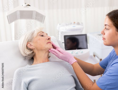 Papier peint Positive aged woman patient lying on clinical chair discussing face aesthetic pr