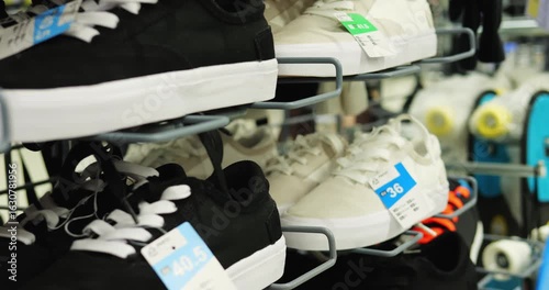 Sports store contains special shoes with price tags to buy branded product. Clean modern sneakers stand on metal stands attracting attention of customers