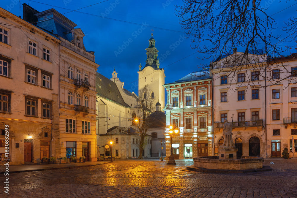 Fototapeta premium Historic buildings and cafes on Market Square in Lviv, Ukraine, at dawn with street lights on