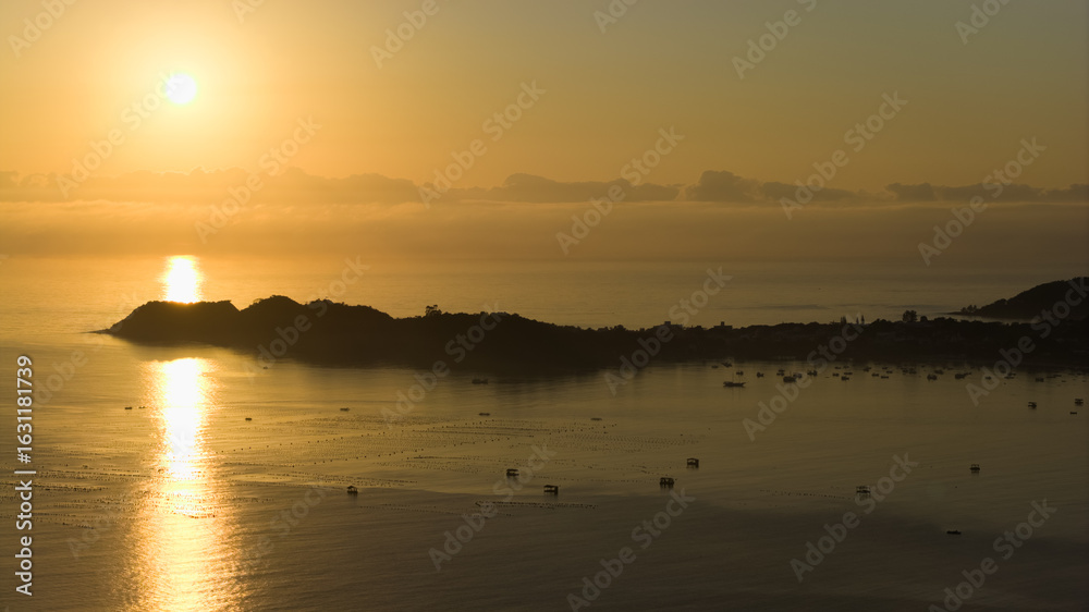Naklejka premium Sunset over the Atlantic Ocean in Brazil with fishing boats scattered across calm waters.