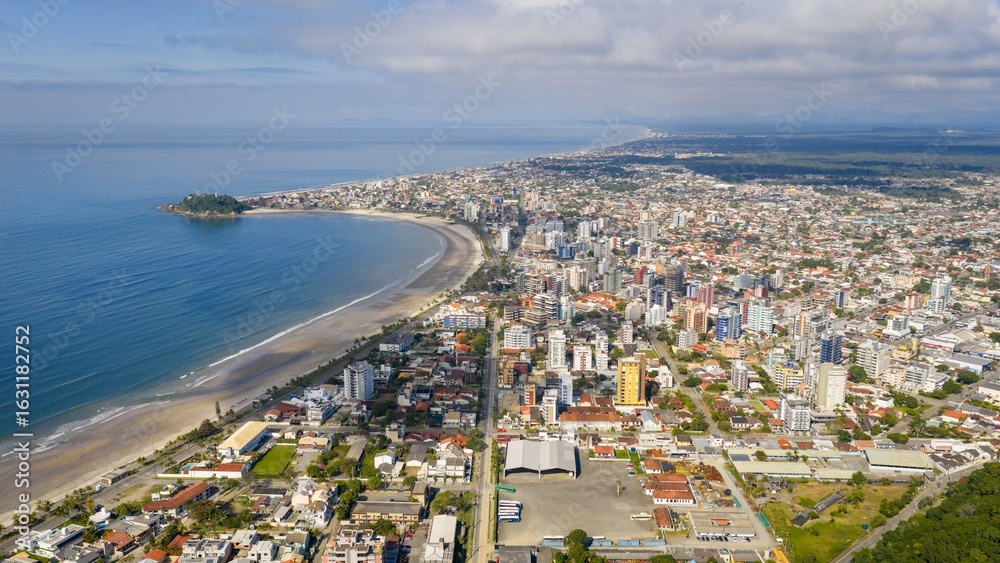 Fototapeta premium Aerial view of Guaratuba city and coastline on the Paraná coast, Brazil, showing buildings and beach.