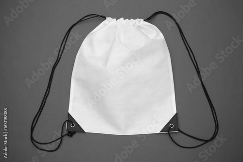 Blank white drawstring backpack mockup with black ropes on a grey background. Empty fabric gym sack for design presentation.