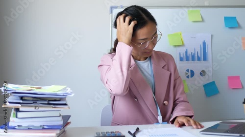 A young female office worker is stressed out by the assigned work. She has not completed her work according to the goals, which makes her irritable and in a bad mood.