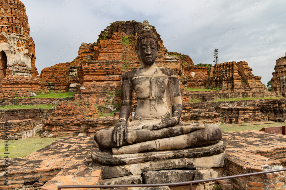 Ancient Buddha statue in front of ruined brick structures at Wat Phra Ram, Ayutthaya, Thailand Ancient Buddha statue in front of ruined brick structures at Wat Phra Ram, Ayutthaya, Thailand